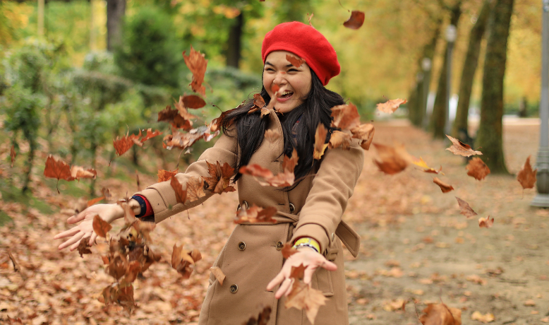 young woman in red hat playing with autumn leaves