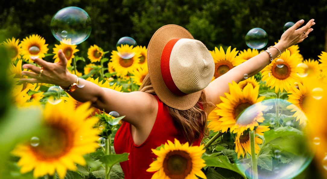Woman in red in field of sunflowers and bubbles