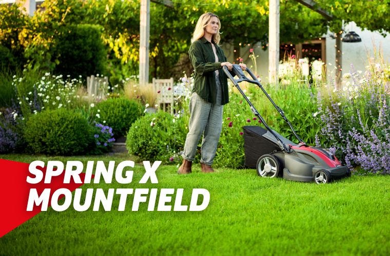 Woman pushing mountfield lawnmower in spring garden